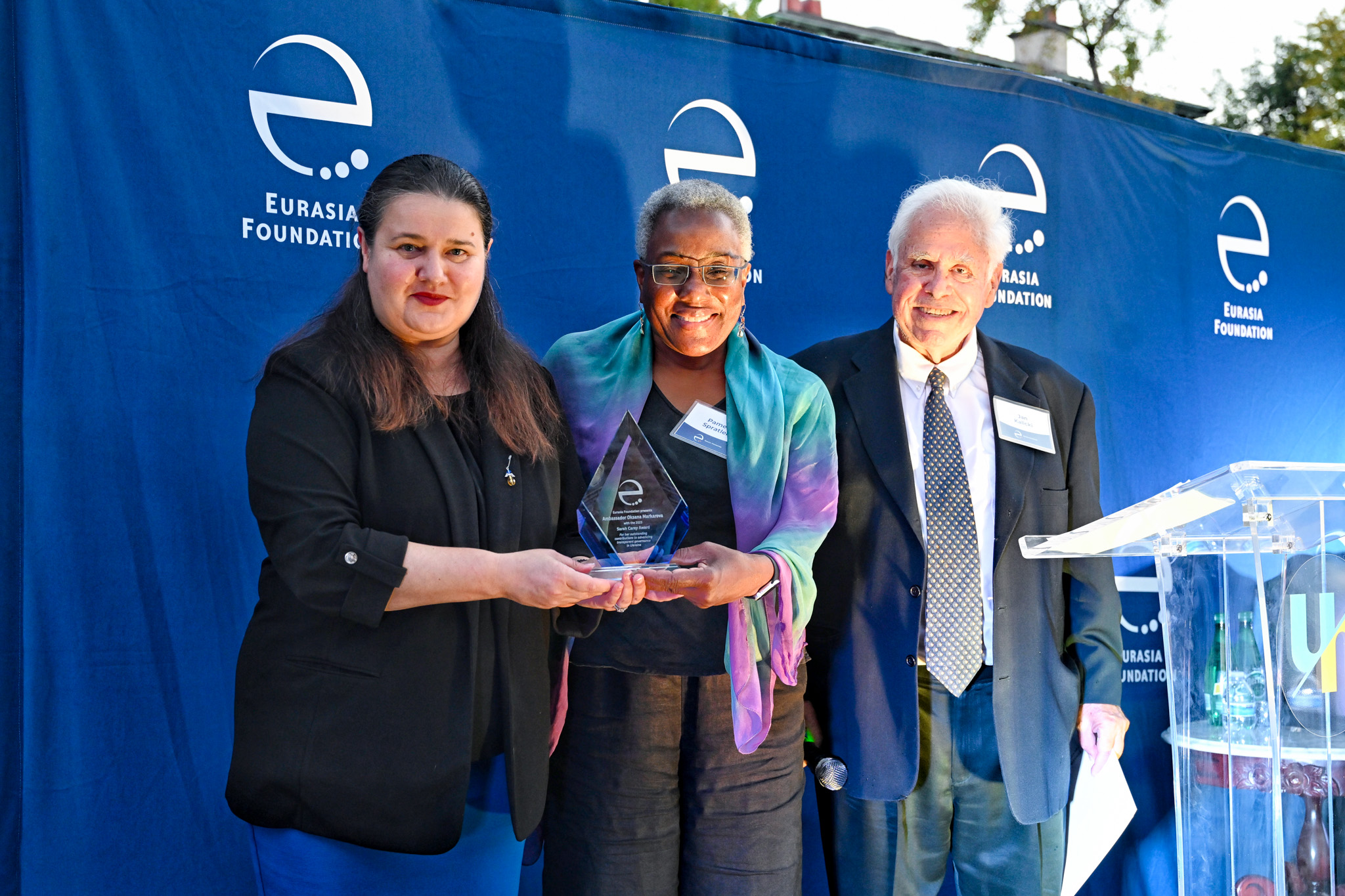 Ambassador Oksana Markarova, EF Chair Pamela L. Spratlen, and EF Chair Emeritus Jan Kalicki hold the Sarah Carey Award, a diamond-shaped glass trophy