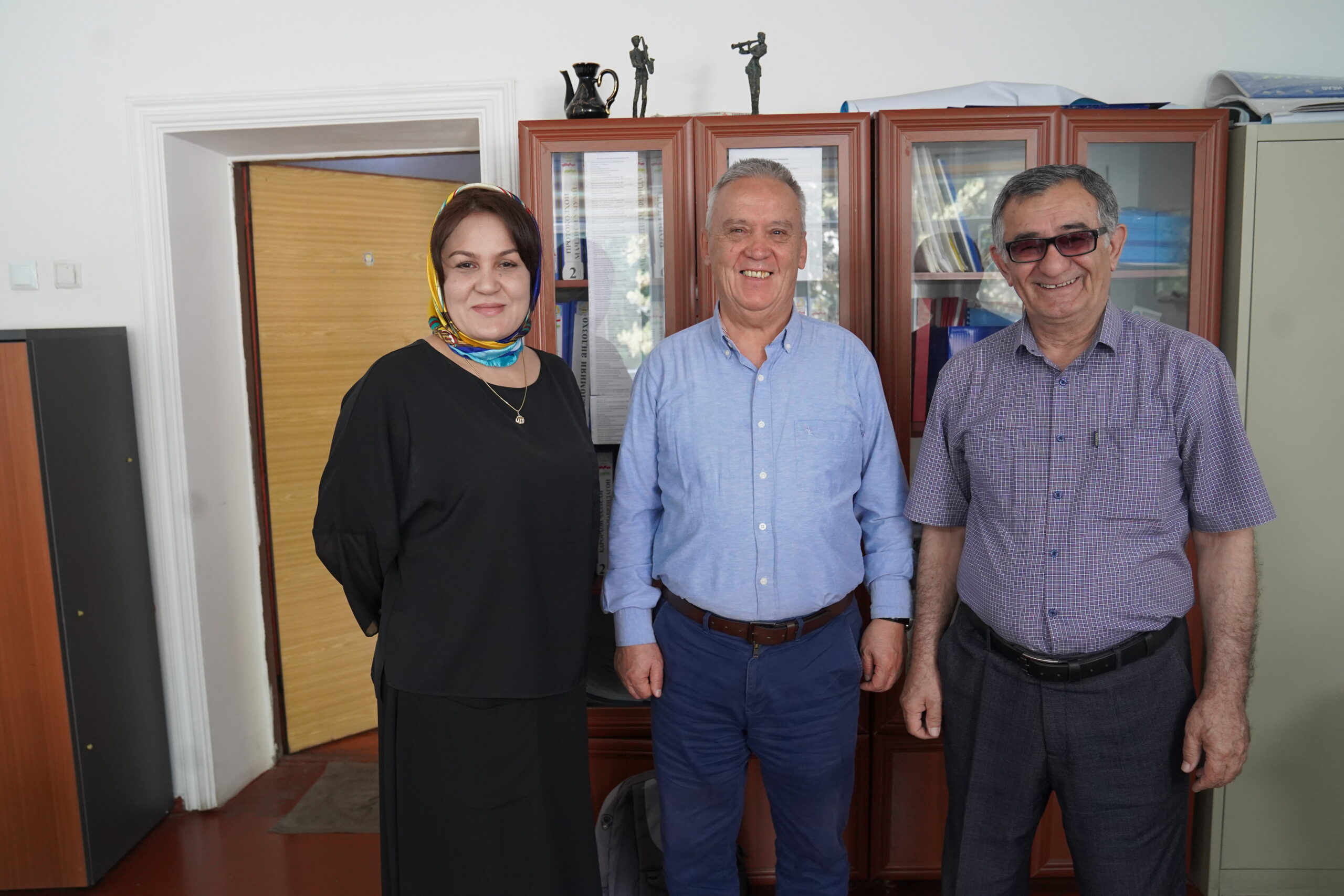 A woman and two men in professional clothing look to the camera.