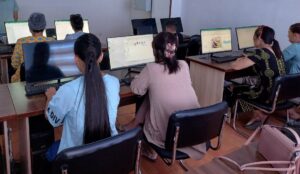 Two women sit and work at computer screens in a computer classroom.