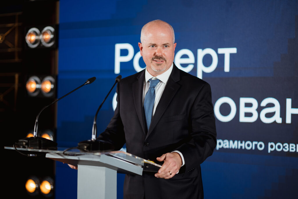 Robert O'Dononvan, EF vice president, speaks at the Ukraine Digital Transformation Activity launch event. A screen behind him shows his name in Ukrainian.