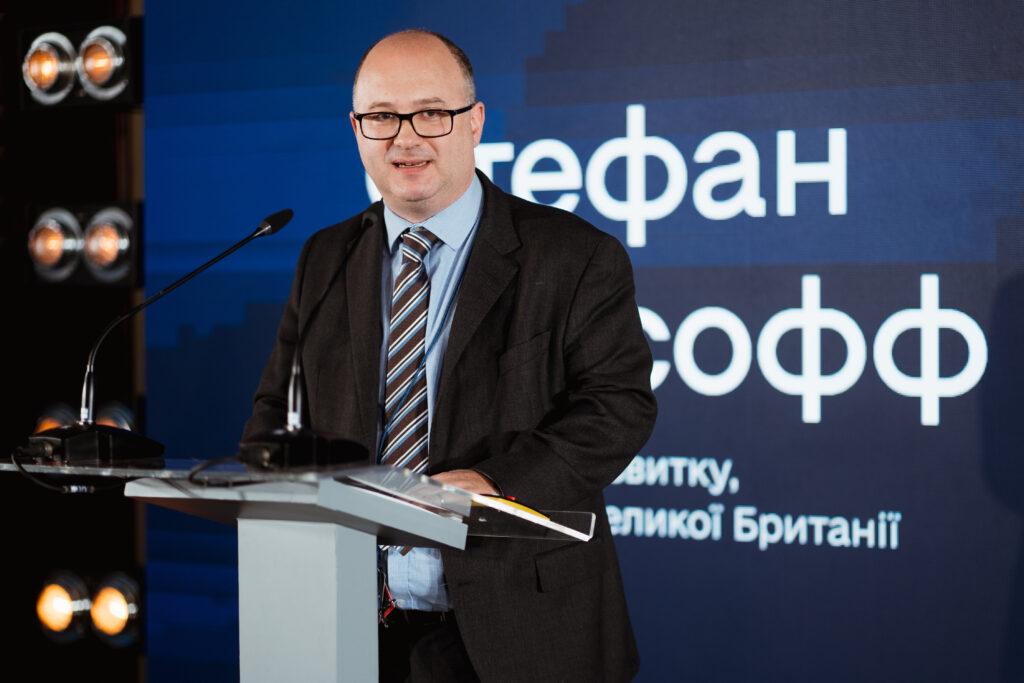 Stefan speaks at the Ukraine Digital Transformation Activity launch event. A large screen behind him shows his name in Ukrainian.