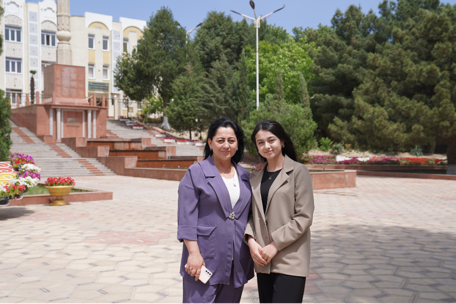 Mother-daughter duo Muqaddas and Nozanin stand in a courtyard between academic building, smiling for the camera.