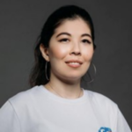 A headshot of Maiya Suyunchaliyeva, a young woman from Kazakhstan. Maiya smiles for the camera and wears a white Central Asia Youth Leadership Academy t-shirt.