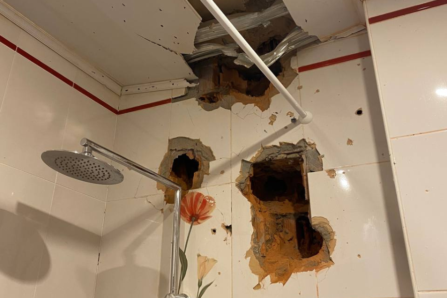 This photo shows severe damage to the walls in Andrii's shower, with multiple holes scattered across the walls and ceiling area.