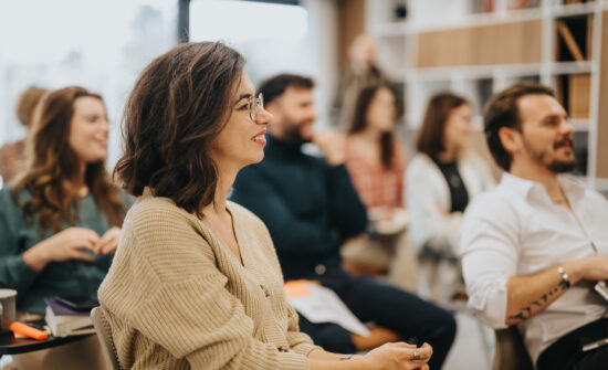 Smiling woman participating in a professional workshop with colleagues in a modern office setting, conveying engagement and teamwork.