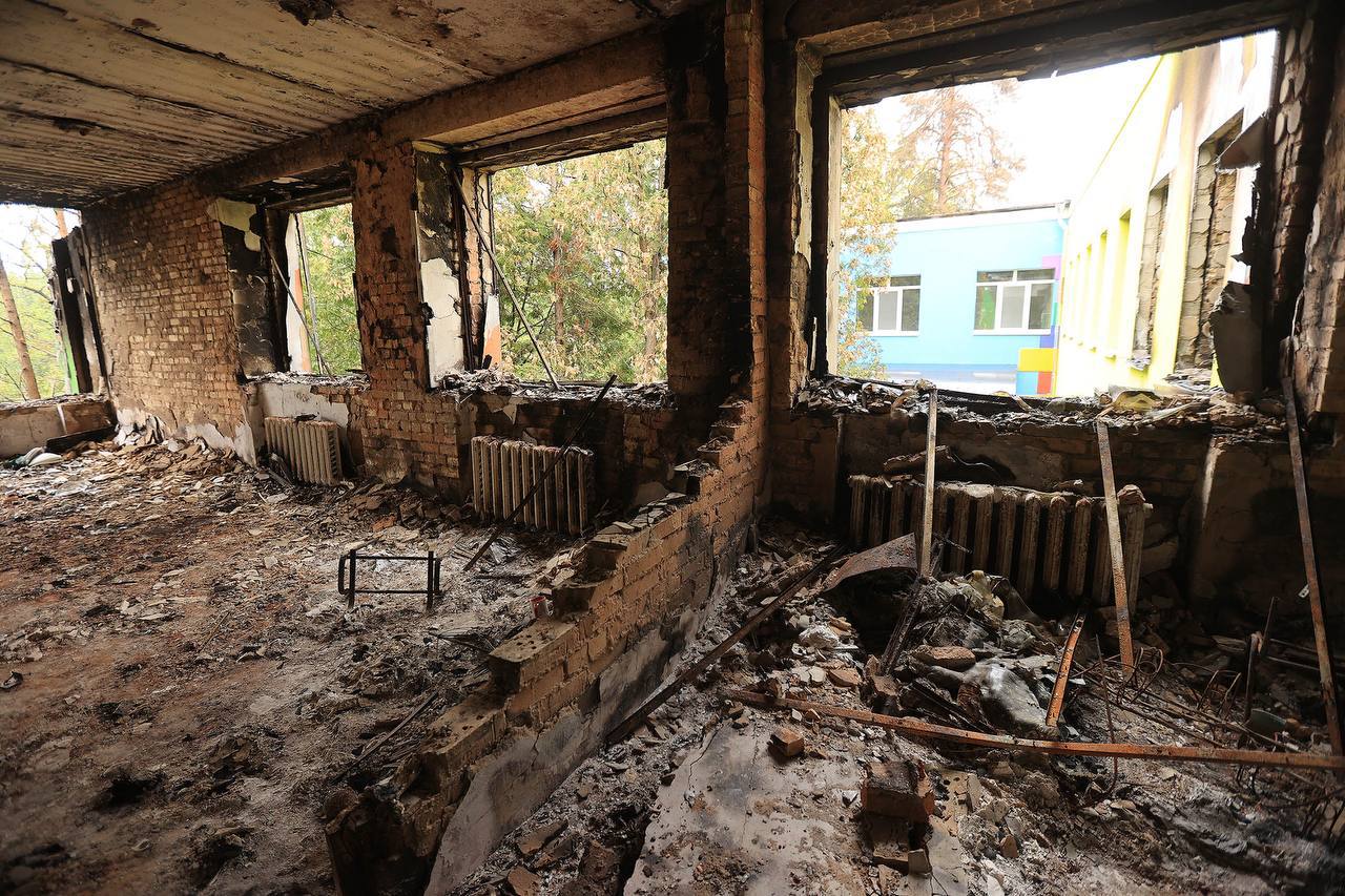 A kindergarten in Ukraine that was destroyed amid the war with Russia. Pictured is a brick building that has been reduced to rubble with four blown out windows and a missing wall.